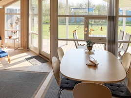Una habitación amplia con un gran ventanal, una mesa redonda y una zona de estar.