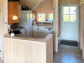 Una cocina con armarios de madera, un refrigerador, un lavavajillas y un lavamanos.