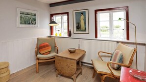 A cozy room with wooden furniture, a radiator, and artwork on the walls. - Rustic Holiday Home in Løkken near Sea (Lokken)
