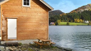 Eine Holzhütte am See mit Picknicktisch und Tür.