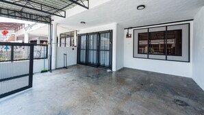 Un'ampia area interna con soffitto alto, grandi finestre a cornice nera e pavimento in cemento.