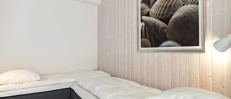 A bedroom with a bed, a window with a picture, and a bedside lamp.
