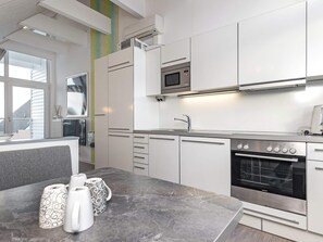 Een moderne keuken met witte kastjes, een ingebouwde magnetron en een roestvrijstalen oven.