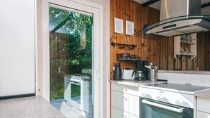 Eine moderne Küche mit weißen Schränken, einer Edelstahl-Dunstabzugshaube und einem großen Fenster mit Blick auf eine Holzterrasse.