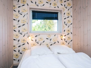 A bedroom with a bed, a window with blinds, and wall-mounted lights.