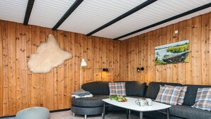 Ein gemütliches Wohnzimmer mit einer Holzwand, einem grauen Sofa, einem weißen Couchtisch und einem flauschigen Teppich.