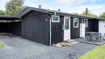 A black building with a number 25, a door, windows, and a table with chairs outside.