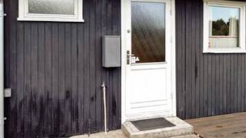 A building with a white door, a small window, and a utility box on the wall.