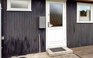 A building with a white door, a small window, and a utility box on the wall. - Mesmerizing Holiday Home in Dannemare near Sea (Dannemare)
