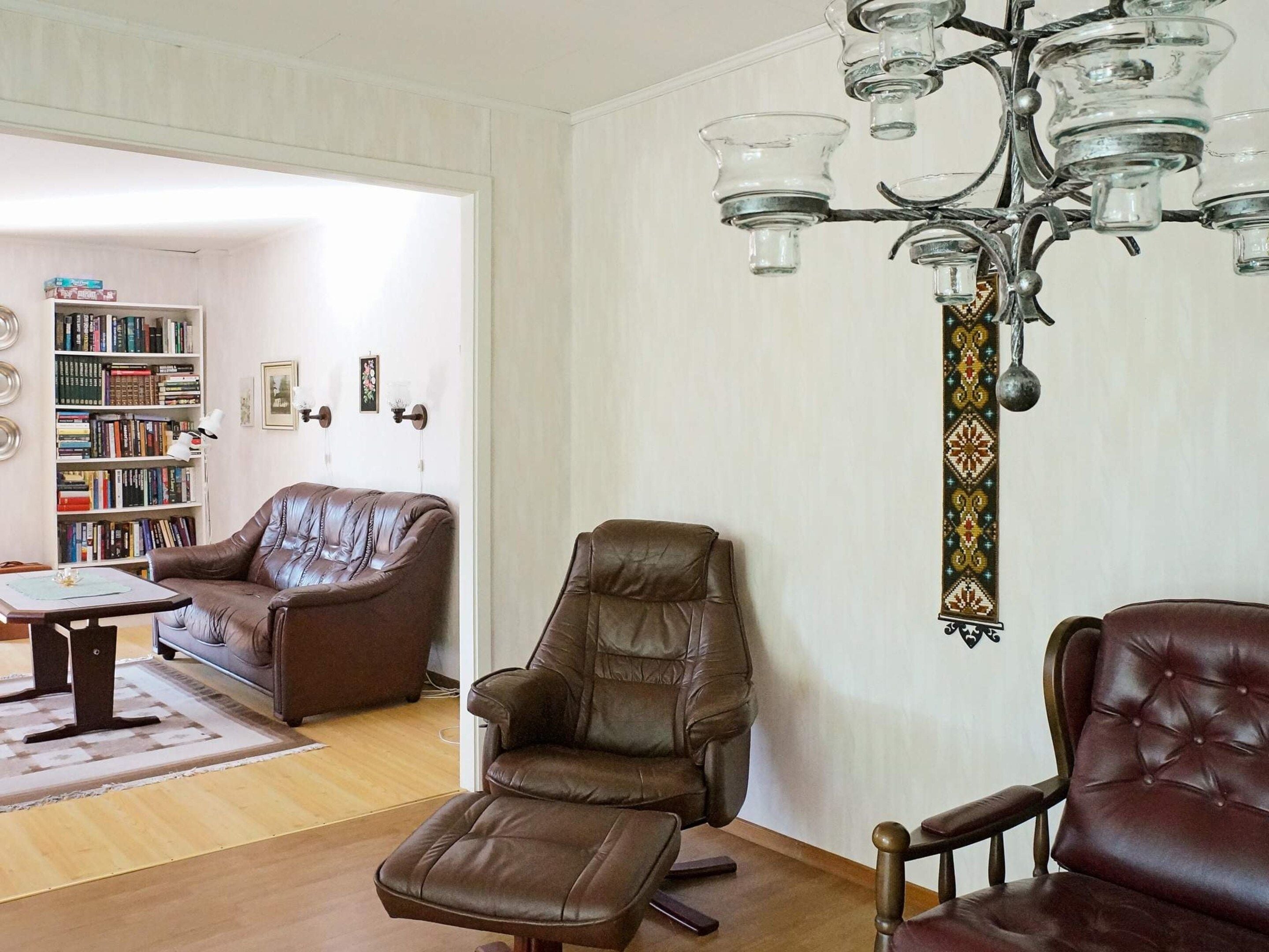 A living room with leather sofas, a coffee table, a bookshelf, and a decorative wall hanging.