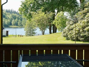 A lakeside view from a wooden deck with a metal railing, a grassy area, and trees. - Holiday Home in Ullared (Ullared)