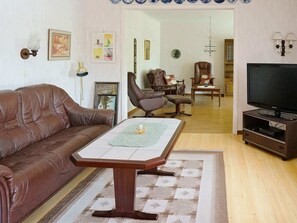 A living room with a brown leather sofa, a wooden coffee table, a TV on a stand, and a patterned rug. - Holiday Home in Ullared (Ullared)