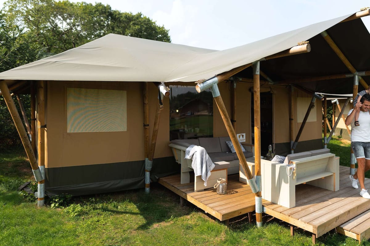 A camping site with a tent, a wooden deck, and a sofa.