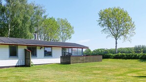 A single-story building with a fenced yard and a large tree in the background. - 4 Person Holiday Home in Laeso (Læsø)