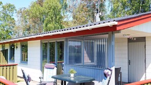 A covered patio with a table and chairs, a small potted plant, and a window with blinds. - 4 Person Holiday Home in Laeso (Læsø)