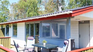 A covered outdoor seating area with a table and chairs, a window with blinds, and a door. - 4 Person Holiday Home in Laeso (Læsø)