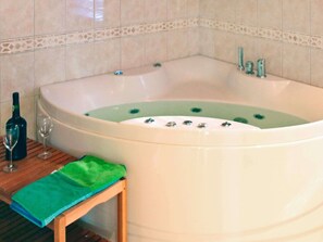 A bathroom with a large bathtub, a wooden stool, a green towel, and a bottle of wine. - 10 Person Holiday Home in Hovden (Bykle)