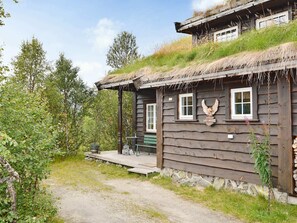 A rustic wooden cabin with a thatched roof, a stone foundation, and a small porch with a bench. - 10 Person Holiday Home in Hovden (Bykle)