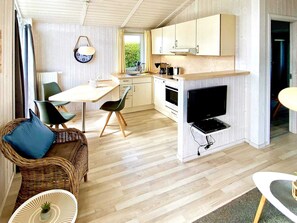A modern kitchen with white cabinets, a built-in oven, and a flat-screen TV.