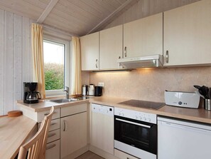 Een moderne keuken met houten kastjes, een ingebouwde oven, een vaatwasser en een koffiezetapparaat.