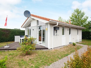 A single-story house with a satellite dish, a door with a number, and a small garden area.