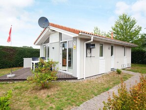 Ein kleines, eingeschossiges Haus mit weißer Fassade und einem Ziegeldach, inklusive Satellitenschüssel.