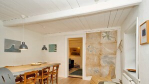 A dining area with a wooden table and chairs, a grill, and pendant lighting. - 2 Person Holiday Home in Gilleleje (Gilleleje)