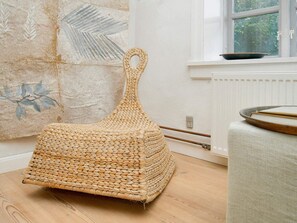 A woven basket chair in a room with a radiator, a window, and a wall with a leaf pattern. - 2 Person Holiday Home in Gilleleje (Gilleleje)
