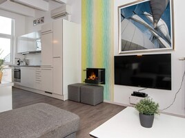 Una sala de estar moderna con chimenea, televisor de pantalla plana y comedor.