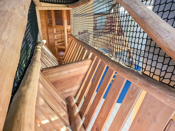 A wooden staircase with a netted enclosure, leading to an upper level. - Holiday Home in Wendtorf (Wendtorf)