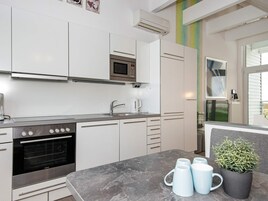 Cocina moderna con armarios blancos, horno empotrado, microondas y cafetera.