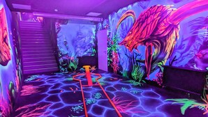 A room with a glowing floor, a red pathway, and a mural of a dragon. - Holiday Home in Wendtorf (Wendtorf)