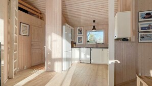 A modern kitchen with wooden paneling, white cabinets, and a window above the sink. - 8 Person Holiday Home in Gedser-by Traum (Gedser)