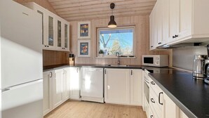 A modern kitchen with white cabinets, a stainless steel refrigerator, a microwave, and a coffee maker. - 8 Person Holiday Home in Gedser-by Traum (Gedser)