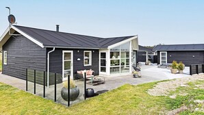 A modern house with a large glass front, a covered patio, and a well-maintained lawn. - 5 Star Holiday Home in Lokken (Lokken)