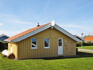 A small, single-story building with a sloped roof, a satellite dish, and a door with a number plate. - Holiday Home in Gelting (Gelting)