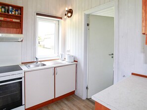 A compact kitchen with a built-in oven, a sink, and a window above it. - Holiday Home in Gelting (Gelting)
