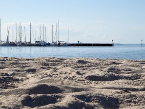 A sandy beach with a row of sailboats docked at a pier. - Holiday Home in Gelting (Gelting)