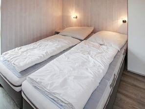A single bed with a wooden headboard and two wall-mounted light fixtures. - Holiday Home in Gelting (Gelting)