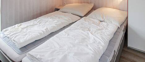 A single bed with a wooden headboard and two wall-mounted light fixtures.