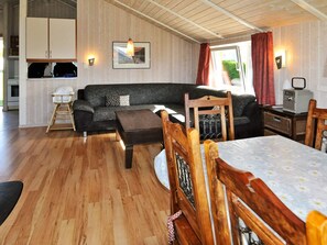 A cozy living room with a sofa, wooden dining table, and chairs. - Holiday Home in Gelting (Gelting)
