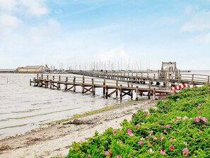 A pier extending into calm waters with a building in the background. - Holiday Home in Gelting (Gelting)