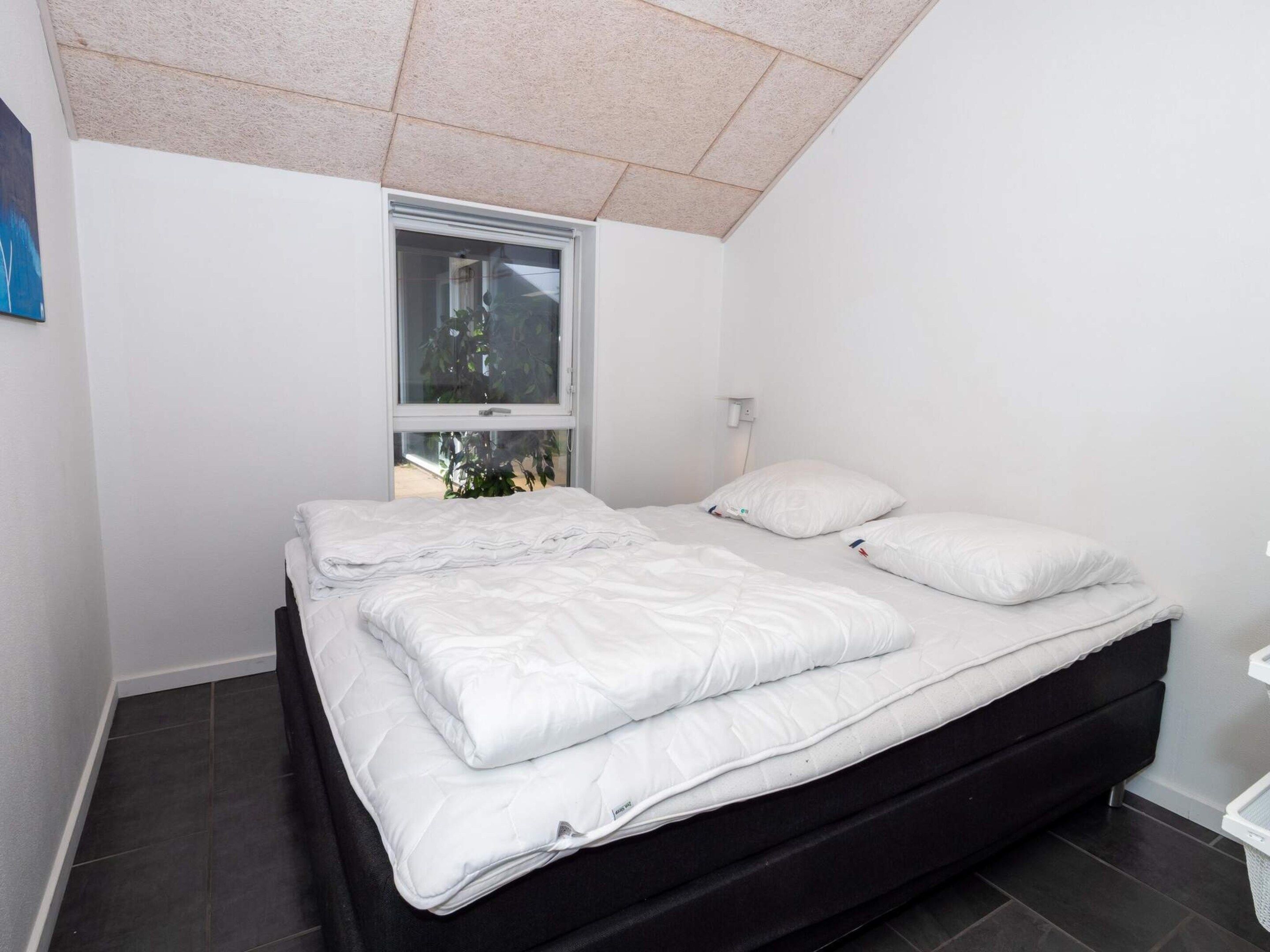 A bedroom with a bed, a window, and a nightstand.