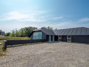 Een modern gebouw met een schuin dak en een oprit van grind.
