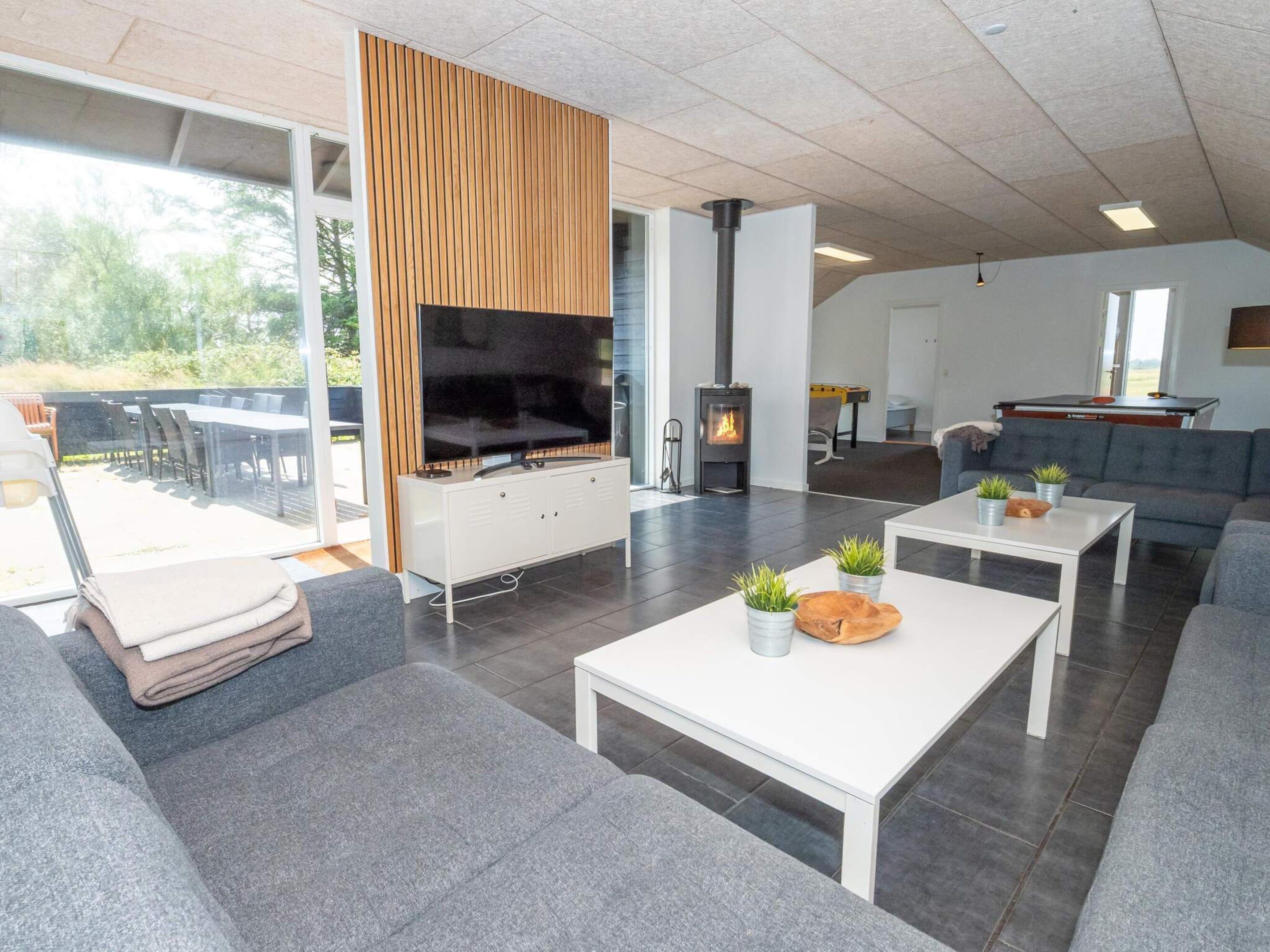 A modern living room with a flat-screen TV, a fireplace, and a dining area with outdoor seating.
