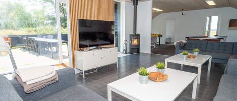 A modern living room with a flat-screen TV, a fireplace, and a dining area with outdoor seating.