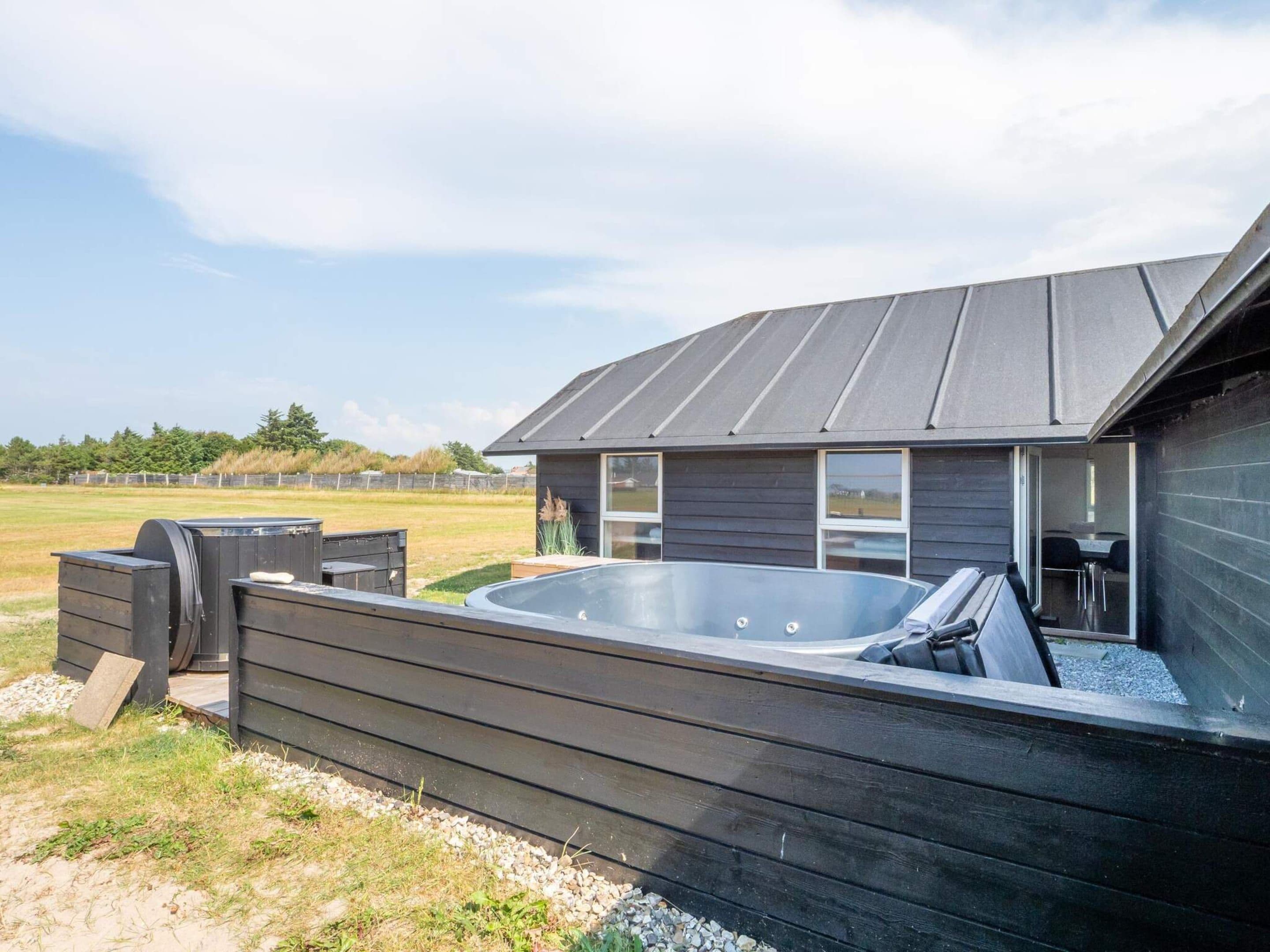 Un edificio moderno con jacuzzi, mobiliario exterior y vistas del paisaje circundante.