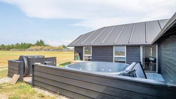 Un edificio moderno con jacuzzi, mobiliario exterior y vistas del paisaje circundante.