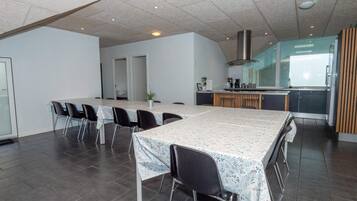 Una cocina moderna con una isla central, un comedor con una mesa larga y sillas, y una puerta visible que conduce a otra habitación.
