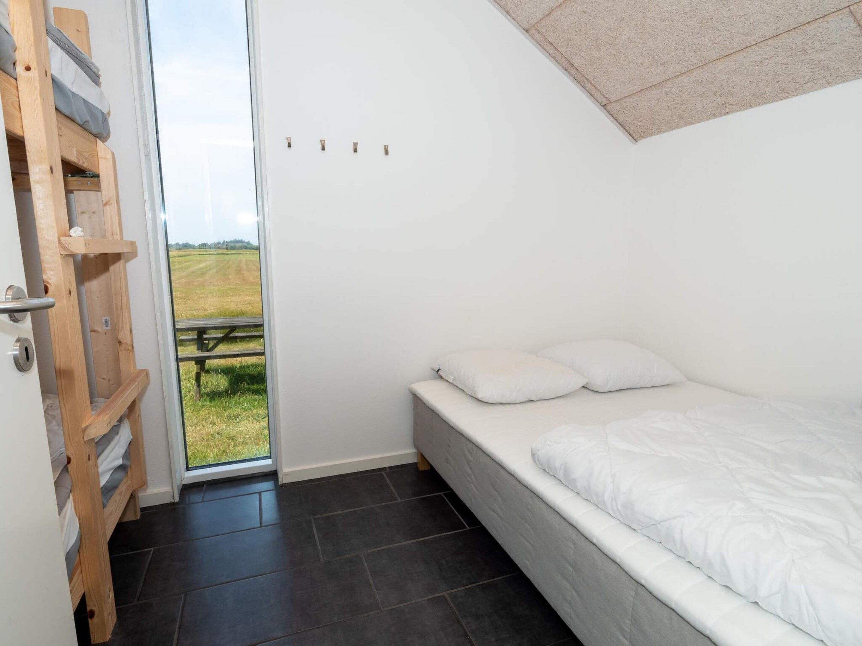 A bedroom with a bed, a wooden ladder, and a door leading to an outdoor area.